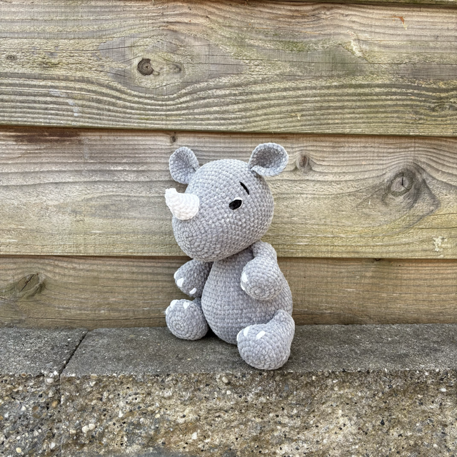 Knuffel Bollie de Neushoorn zit schuin voor de camera, te koop bij De Garengarage